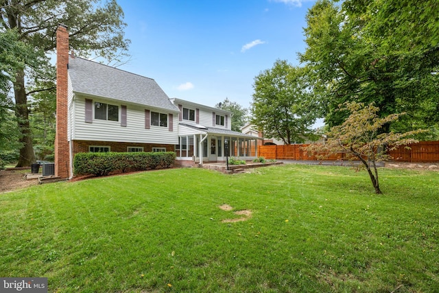 rear view of house featuring a patio, a yard, and a sunroom