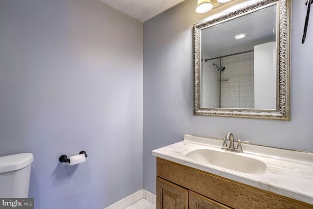 bathroom featuring vanity, toilet, a tile shower, and tile patterned flooring