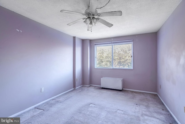 unfurnished room with ceiling fan, a textured ceiling, and light colored carpet