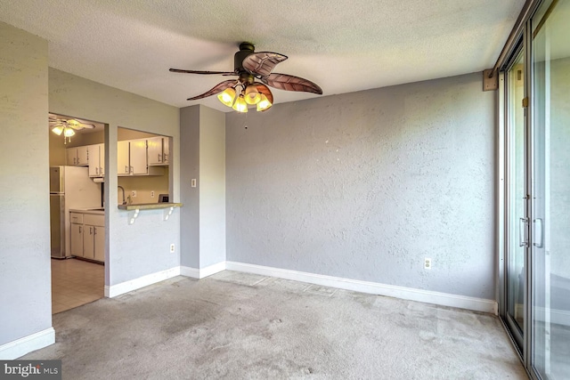 interior space featuring light carpet, a textured ceiling, and ceiling fan