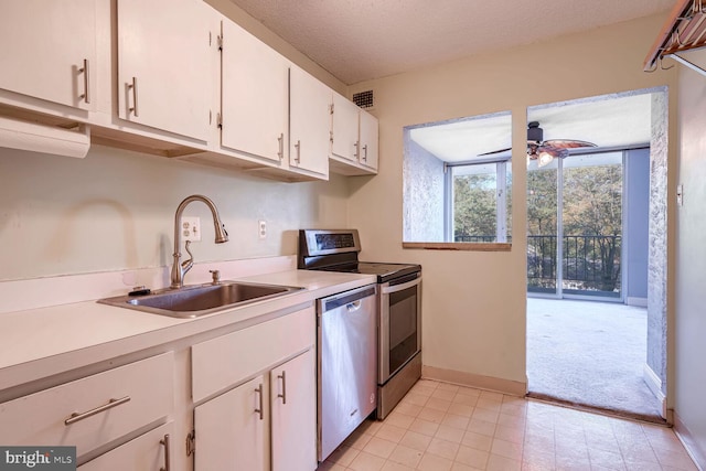 kitchen featuring appliances with stainless steel finishes, sink, a textured ceiling, white cabinets, and light colored carpet