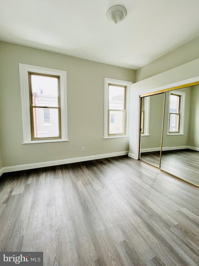 unfurnished bedroom with multiple windows, hardwood / wood-style flooring, and a closet