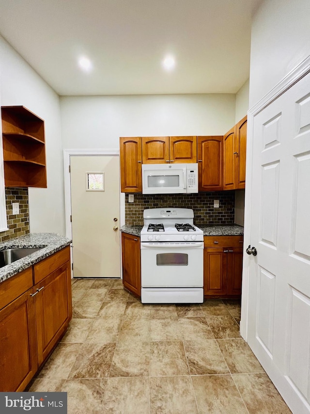 kitchen with white appliances, light stone counters, sink, and decorative backsplash