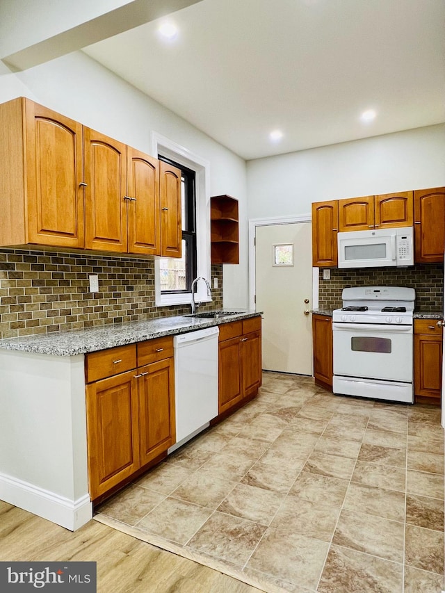 kitchen featuring white appliances, a wealth of natural light, light stone counters, and backsplash