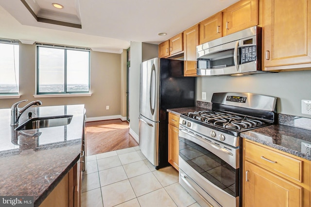 kitchen with dark stone counters, light wood-type flooring, appliances with stainless steel finishes, and sink