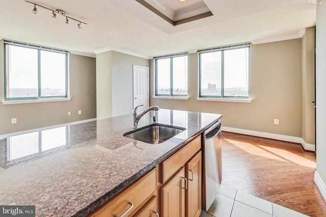 kitchen with dark stone counters, a wealth of natural light, light hardwood / wood-style floors, and sink