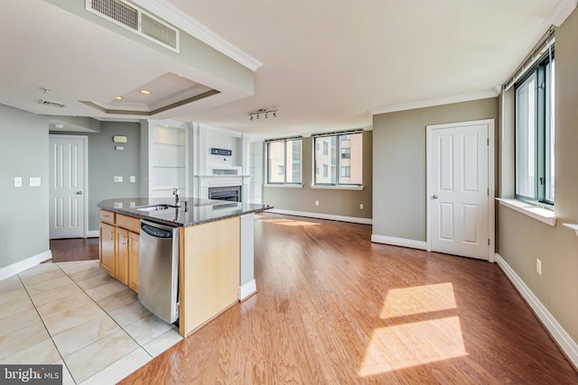 kitchen featuring dishwasher, a center island with sink, sink, and light hardwood / wood-style flooring