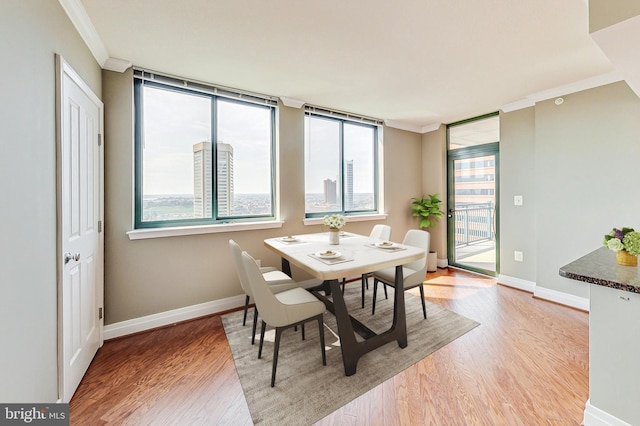 dining space featuring light wood-type flooring and crown molding