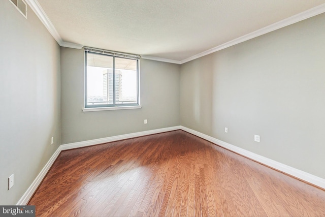 empty room featuring ornamental molding, a textured ceiling, and hardwood / wood-style flooring