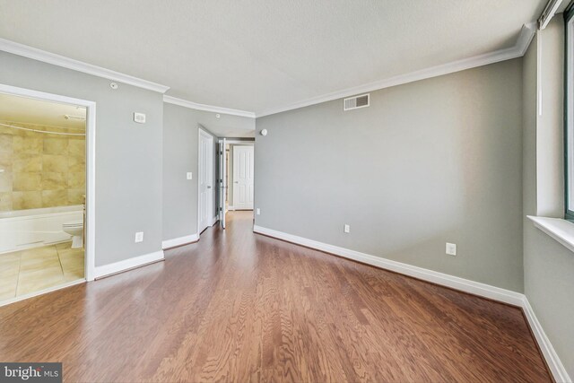 spare room featuring a textured ceiling, wood-type flooring, and ornamental molding