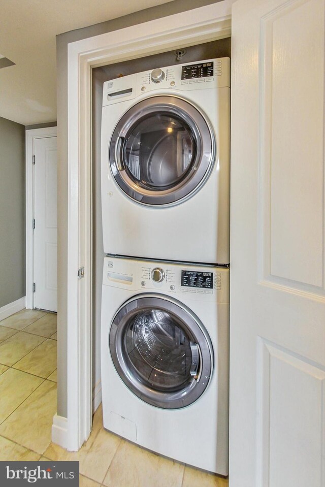 laundry room with stacked washer and clothes dryer and light tile patterned flooring