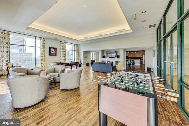 rec room with a raised ceiling, hardwood / wood-style floors, and billiards