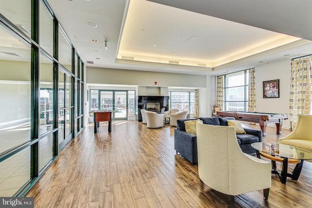 living room with hardwood / wood-style floors, a raised ceiling, and billiards