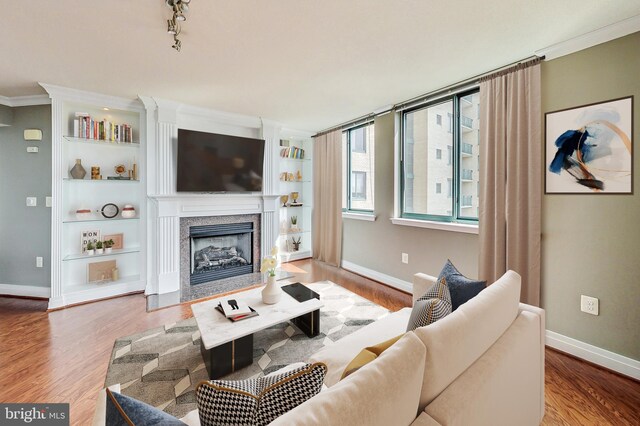 living room featuring ornamental molding, hardwood / wood-style floors, built in features, and a premium fireplace