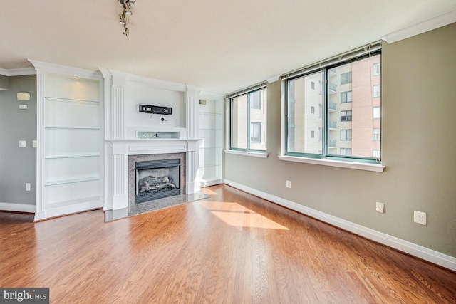 unfurnished living room with wood-type flooring, crown molding, and built in features