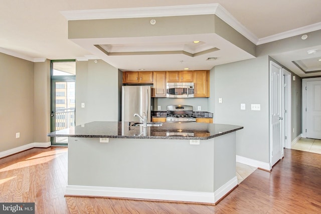 kitchen featuring light wood-type flooring, a kitchen island with sink, sink, appliances with stainless steel finishes, and crown molding