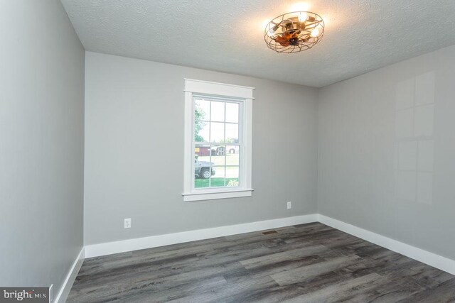 empty room with a textured ceiling and dark wood-type flooring