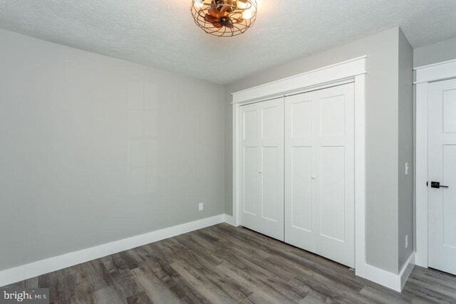 unfurnished bedroom featuring a closet, dark hardwood / wood-style floors, and a textured ceiling