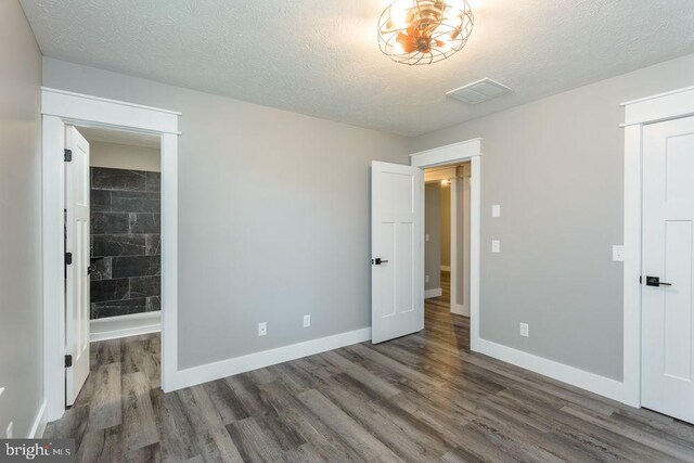 unfurnished bedroom with dark hardwood / wood-style flooring and a textured ceiling