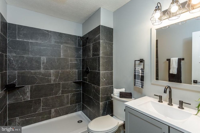 bathroom with tiled shower, toilet, a textured ceiling, and vanity