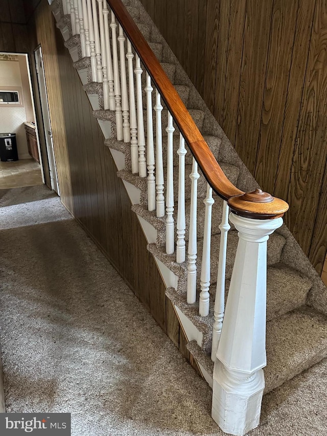 stairway with carpet and wood walls