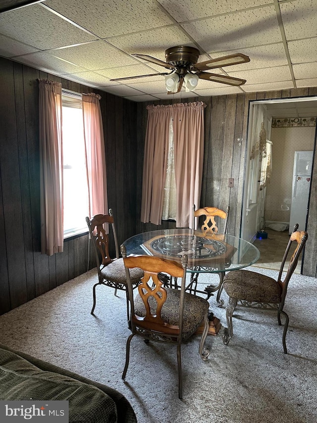 dining area featuring a healthy amount of sunlight, ceiling fan, and wooden walls