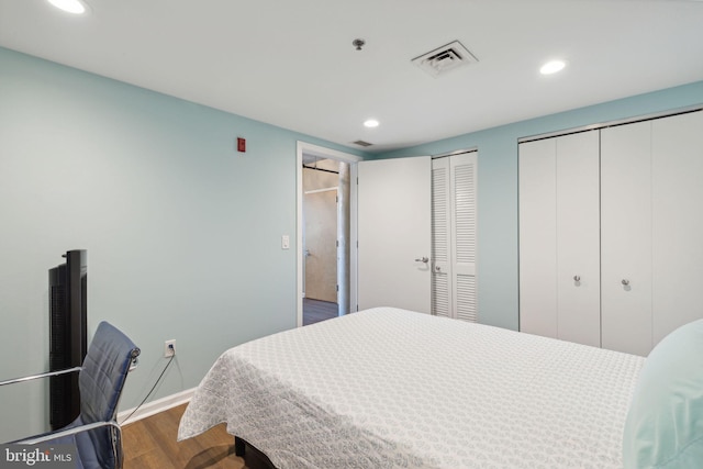 bedroom with wood-type flooring and multiple closets