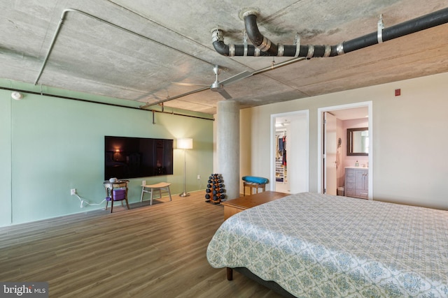 bedroom with ceiling fan, wood-type flooring, a closet, a spacious closet, and ensuite bath