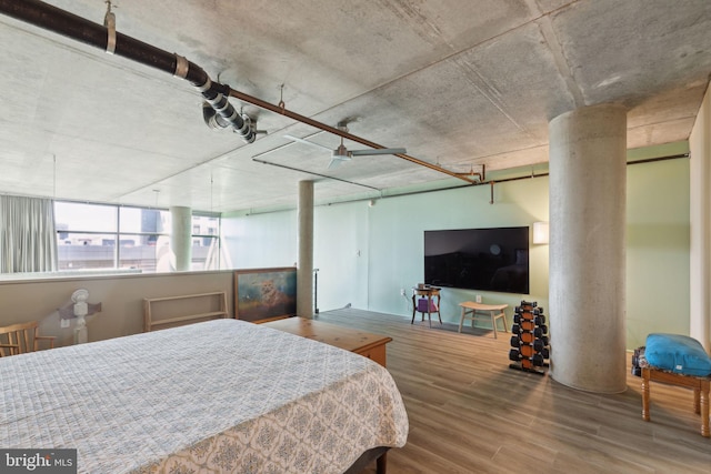 bedroom with wood-type flooring and decorative columns