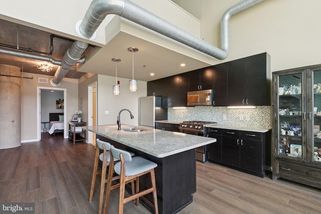 kitchen with decorative light fixtures, sink, appliances with stainless steel finishes, and light hardwood / wood-style floors