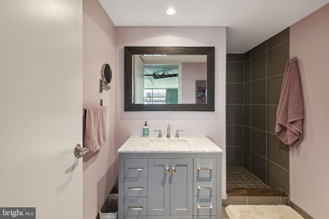 bathroom featuring tiled shower and vanity