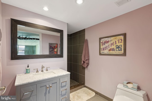 bathroom featuring tiled shower, vanity, toilet, and tile patterned flooring