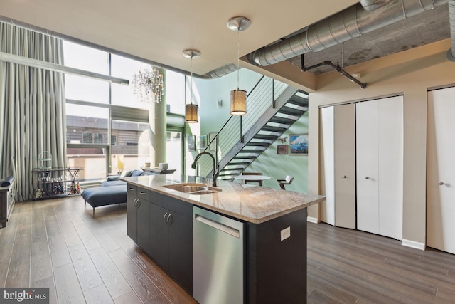 kitchen featuring stainless steel dishwasher, a kitchen island with sink, dark hardwood / wood-style floors, and decorative light fixtures