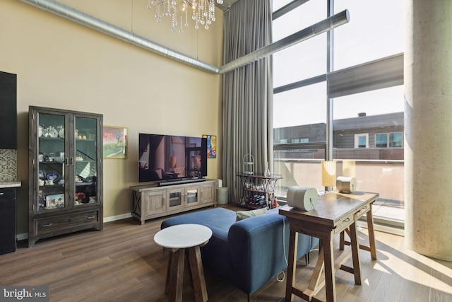 living room featuring wood-type flooring, a high ceiling, and an inviting chandelier