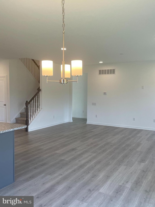 empty room with wood-type flooring and a notable chandelier