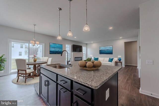 kitchen featuring decorative light fixtures, light hardwood / wood-style flooring, stainless steel appliances, sink, and light stone counters