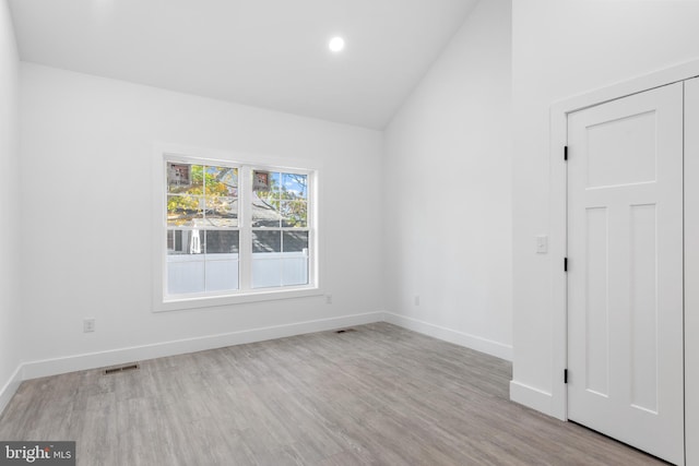 empty room with light hardwood / wood-style floors and vaulted ceiling