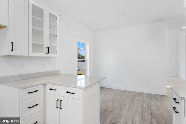 kitchen with white cabinetry, kitchen peninsula, and light wood-type flooring