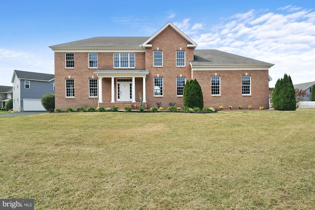 colonial inspired home featuring a front lawn and a garage