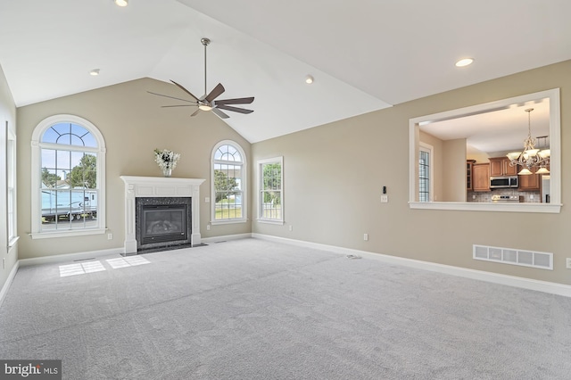 unfurnished living room with ceiling fan with notable chandelier, a premium fireplace, and light colored carpet