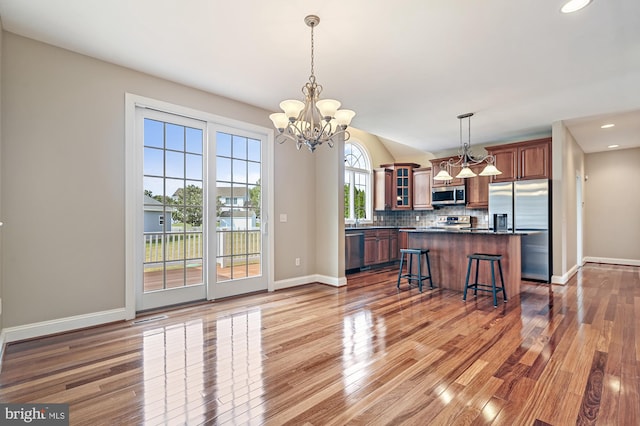 kitchen featuring appliances with stainless steel finishes, an inviting chandelier, a kitchen breakfast bar, and pendant lighting