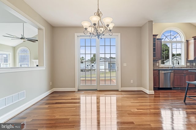 doorway featuring hardwood / wood-style flooring, ceiling fan with notable chandelier, and lofted ceiling