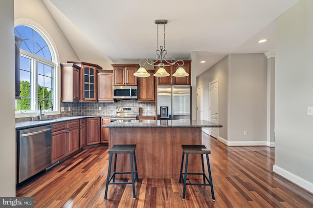 kitchen featuring dark stone counters, appliances with stainless steel finishes, a kitchen island, and dark hardwood / wood-style flooring