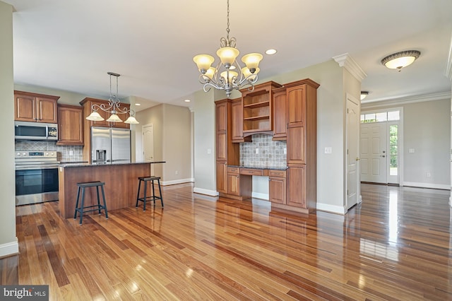 kitchen with a chandelier, tasteful backsplash, a kitchen island, appliances with stainless steel finishes, and ornamental molding