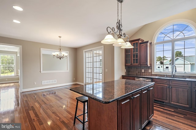 kitchen with a kitchen island, a kitchen bar, dark hardwood / wood-style floors, sink, and a notable chandelier