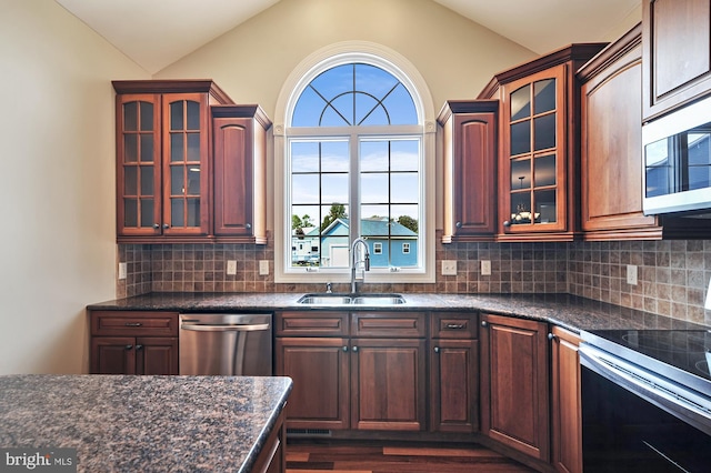 kitchen with decorative backsplash, vaulted ceiling, appliances with stainless steel finishes, and sink