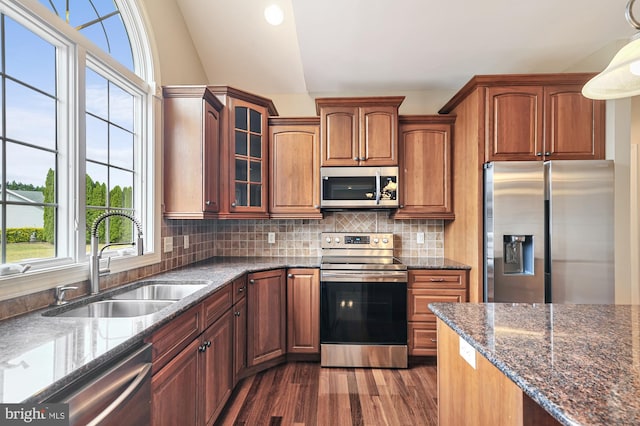 kitchen featuring appliances with stainless steel finishes, dark wood-type flooring, pendant lighting, lofted ceiling, and sink