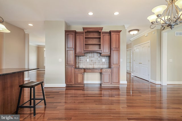 kitchen with tasteful backsplash, pendant lighting, crown molding, an inviting chandelier, and dark hardwood / wood-style floors