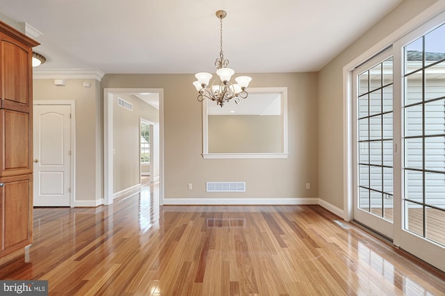 empty room with an inviting chandelier, light hardwood / wood-style flooring, crown molding, and a wealth of natural light