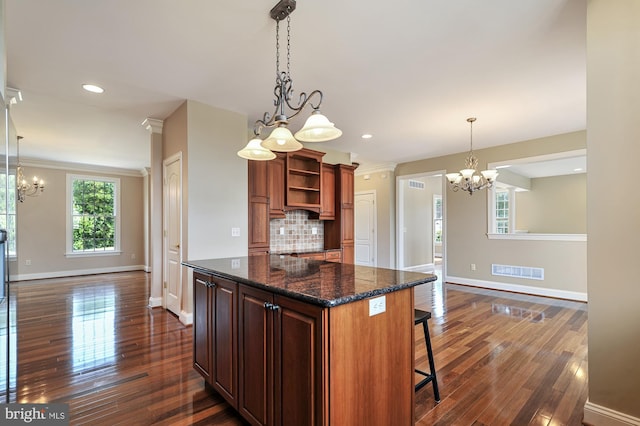 kitchen featuring tasteful backsplash, a breakfast bar, a center island, dark hardwood / wood-style floors, and a chandelier